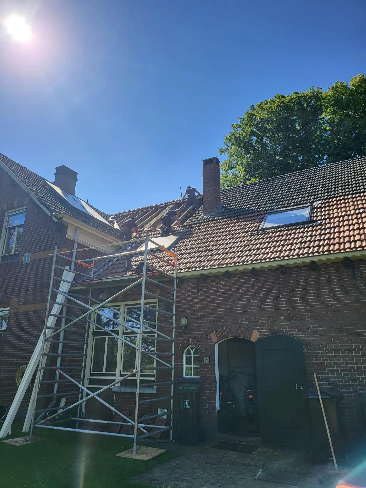 Steiger tegen een bakstenen woning tijdens de renovatie van het pannendak