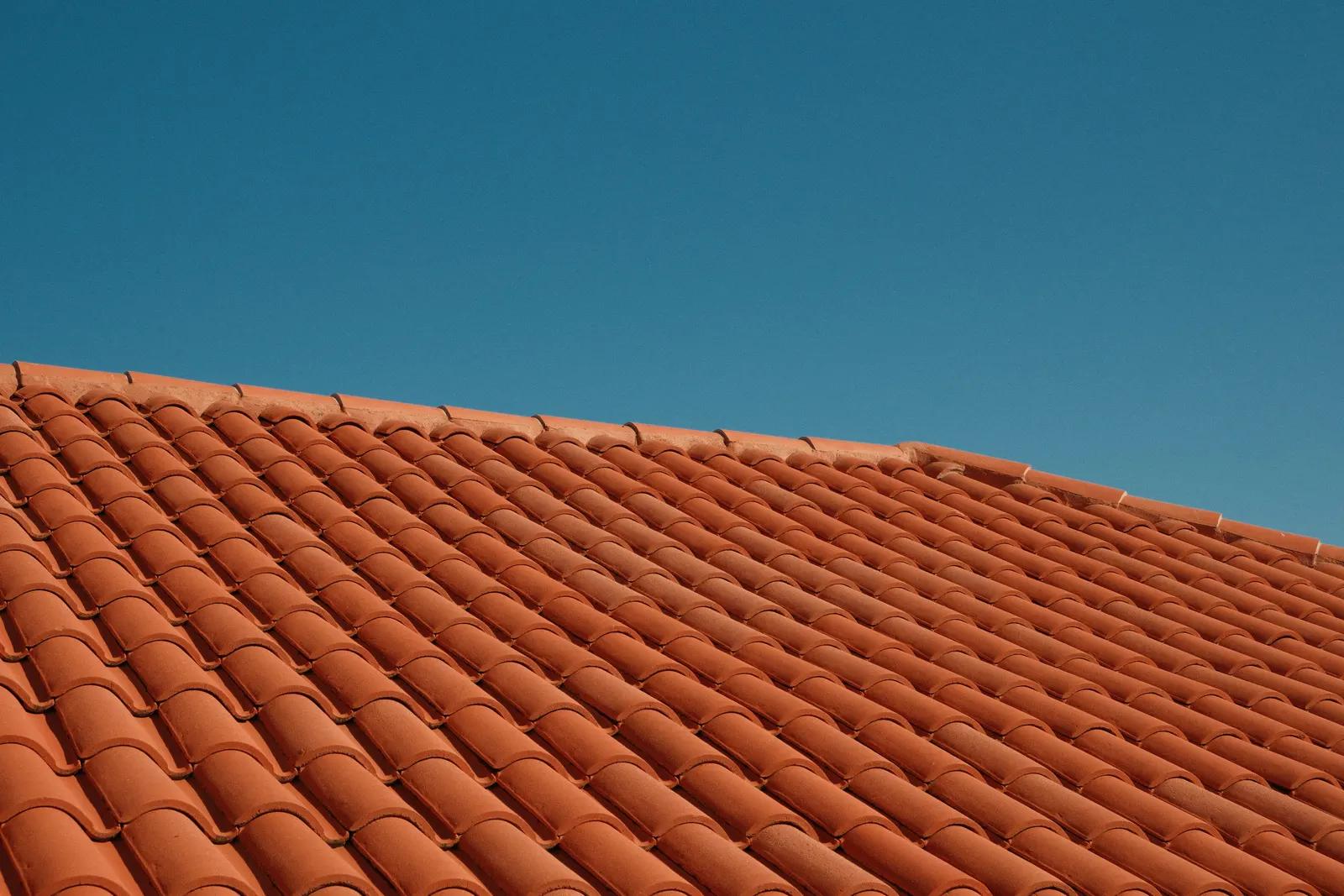 Rode dakpannen op een schuin dak tegen een blauwe lucht